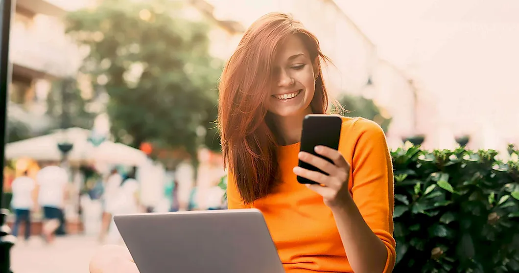 Schöne glückliche Frau draußen mit Laptop